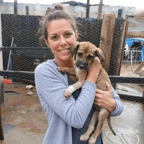Janete da Silva holding a rescued puppy at one of the places we deliver food to